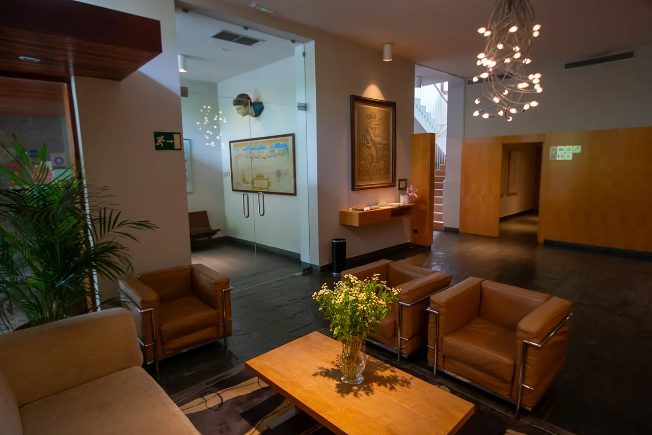 Salón del hotel con butacas, mesa y lámpara escultórica