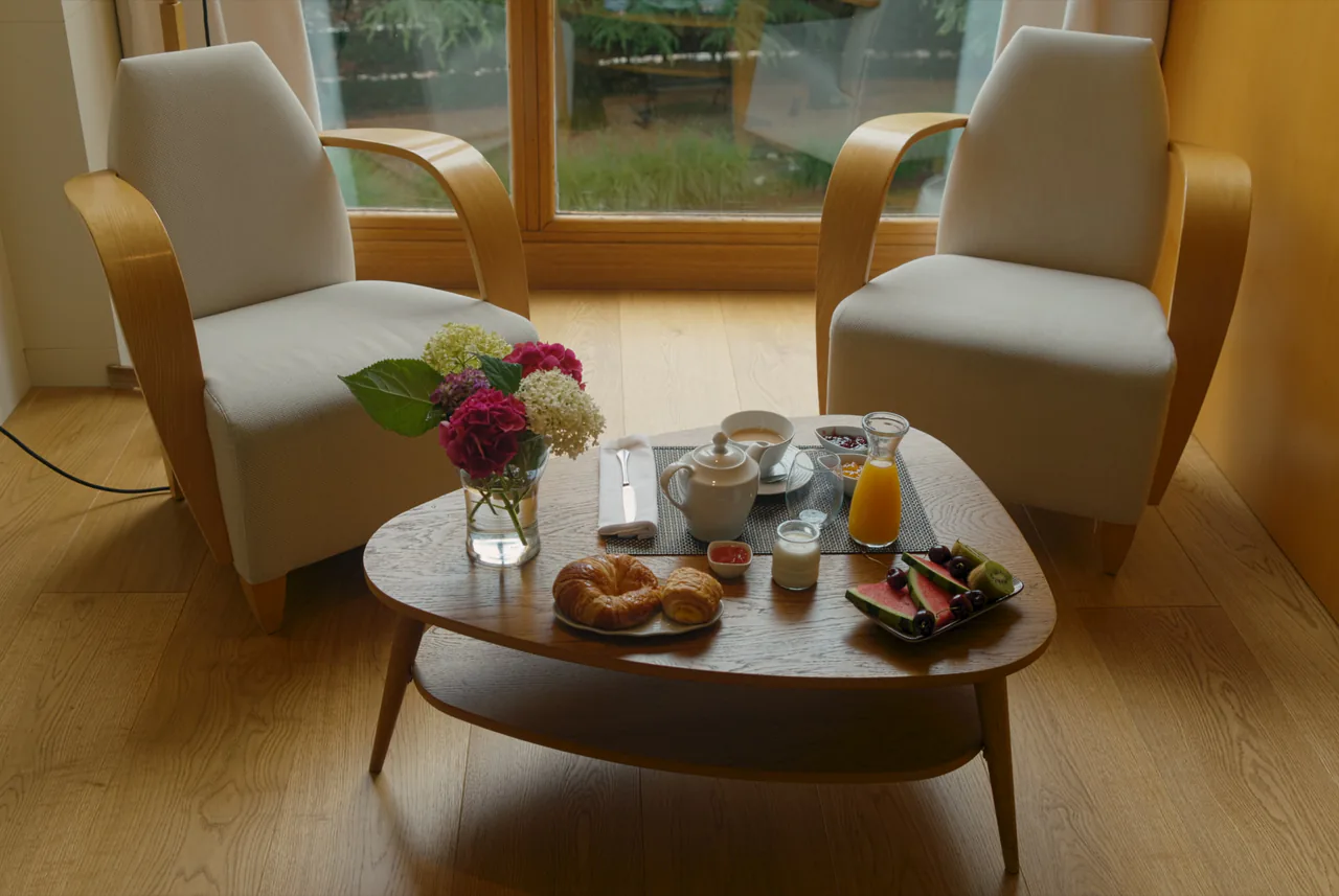 Desayuno servido en la mesa de la habitación entre dos butacas
