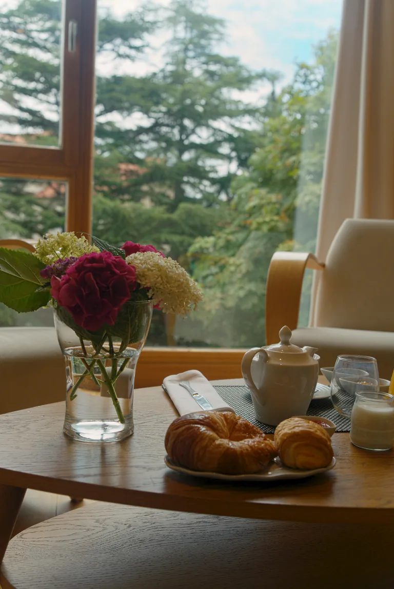 Detalle del desayuno en la habitación: flores, cruasanes y tetera junto al ventanal